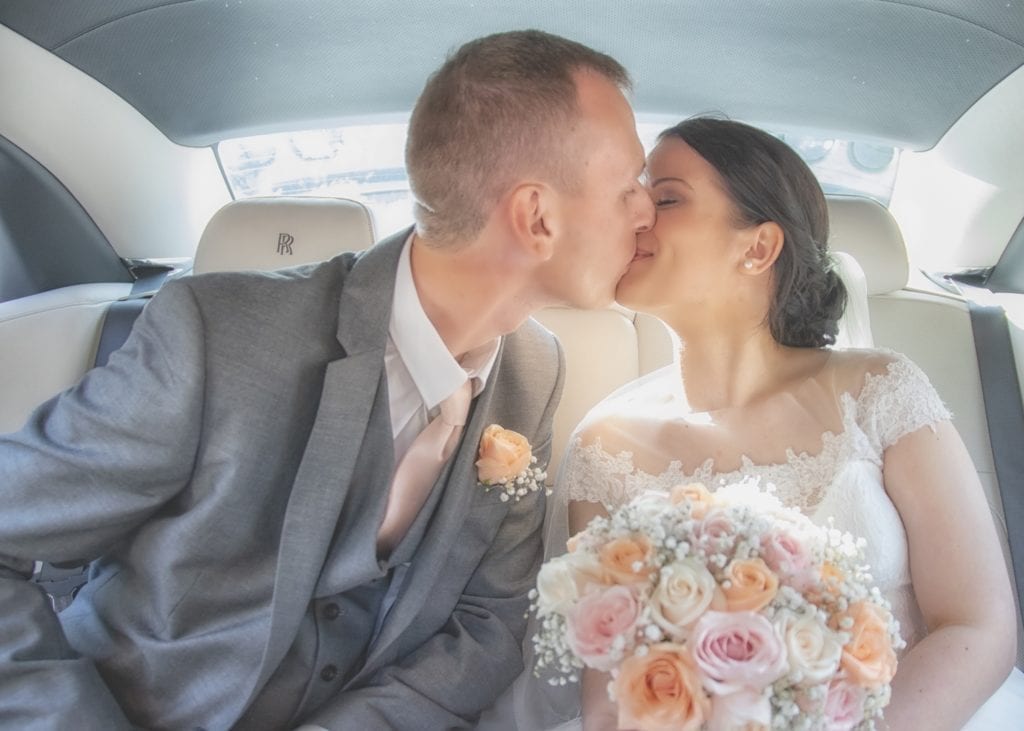 photo of bride and groom kissing in the back of the wedding car